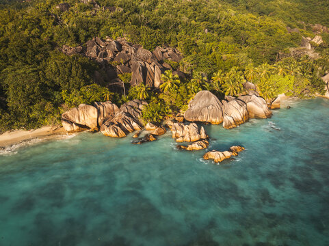 Aerial view of Anse Source d'Argent beach featuring iconic granite rock formations, turquoise ocean water, and lush tropical palm trees in L'Union Estate, Seychelles.