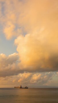 Time lapse of the beautiful morning clouds over the ocean in Bali Indonesia at sunrise. Cardgo ships can be seen in the distance. Vertical Video.