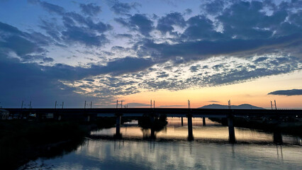 Fototapeta premium Evening view of Nakanokuchi River and railway bridge from Sado Bridge in Tsubame City, Niigata