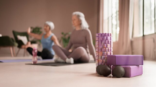 Two senior women friends practicing side body stretches during yoga class