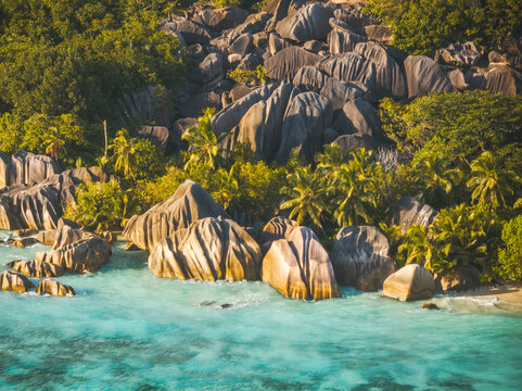 Aerial view of the iconic granite boulders of Anse Source d'Argent beach with turquoise waters and lush palm trees in L'Union Estate, Seychelles.