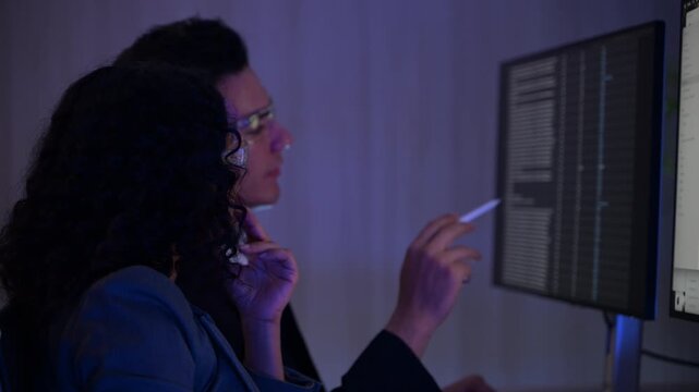 Diverse IT professional computer programmers working late in office developing software code on screen. Happy software engineers team collaborating on digital security system cyber data analysis.