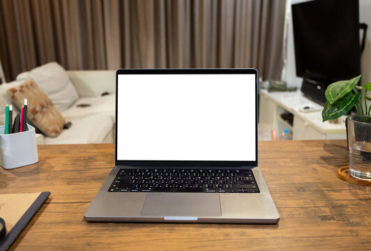 laptop computer with blank white screen, with workspace and office supplies on a wooden desk