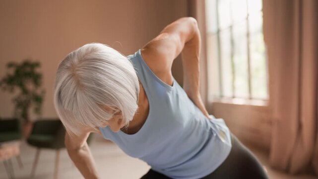 Sad senior woman in sportswear feeling lower back pain during yoga session