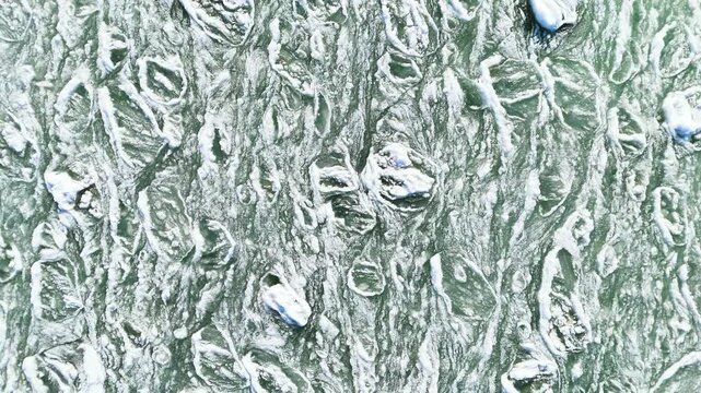 Aerial view of frozen sea with floating ice floes and slush.