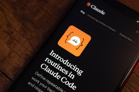 Mexico City, MEXICO - Apr 20 2026 : Close-up of an iPhone on a wooden surface displaying the Anthropic Claude blog announcing the introduction of routines in Claude Code, an AI coding tool.