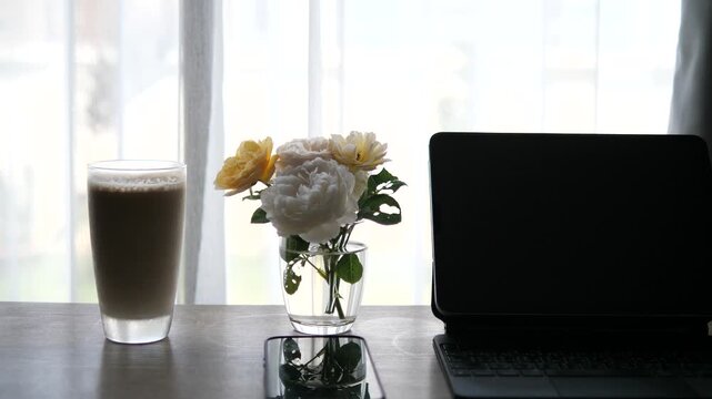 Iced Coffee Latte and Yellow Roses on Desk Near Window
