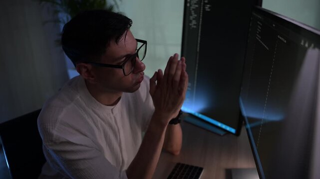Focused young female software developer programming code on multiple monitors in a dark home office at night. Professional woman engineer working on cyber security and data science tech project.
