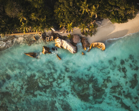 Aerial view of Anse Source d'Argent beach with granite boulders, turquoise water, and palm trees in L'Union Estate, Seychelles.