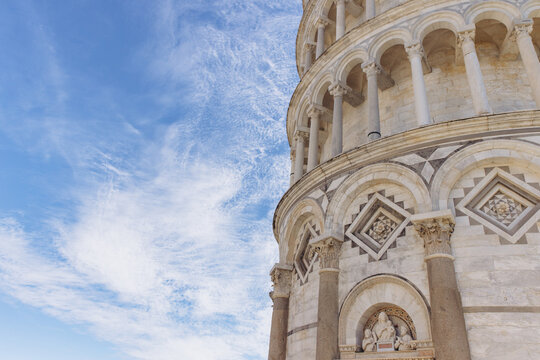 Leaning Tower of Pisa architectural detail with neoclassical style columns and marble decorations under a daytime blue sky