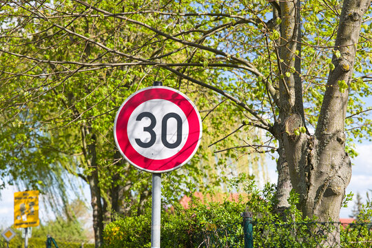 Tempo-30-Verkehrsschild vor gr&uuml;nen B&auml;umen in nat&uuml;rlicher Umgebung.