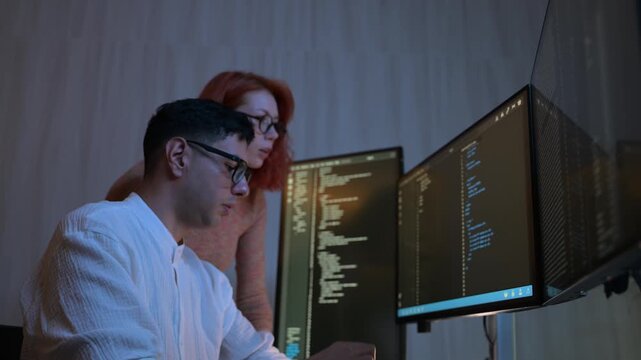 Two software developers collaborating at night, focusing on code review and debugging process on a computer screen, representing teamwork, innovation, and modern software development workflow.