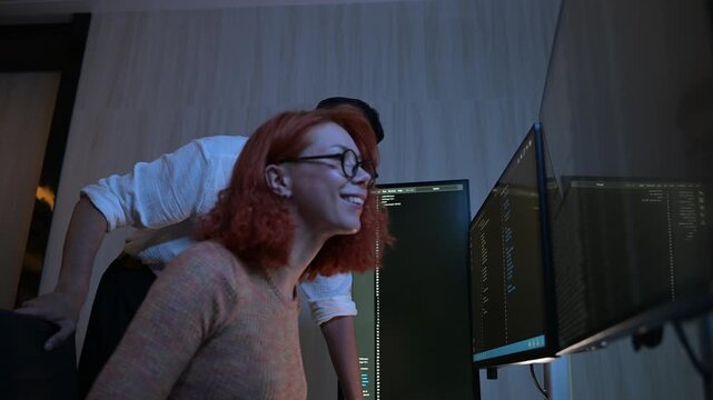 Two software developers collaborating at night, focusing on code review and debugging process on a computer screen, representing teamwork, innovation, and modern software development workflow.