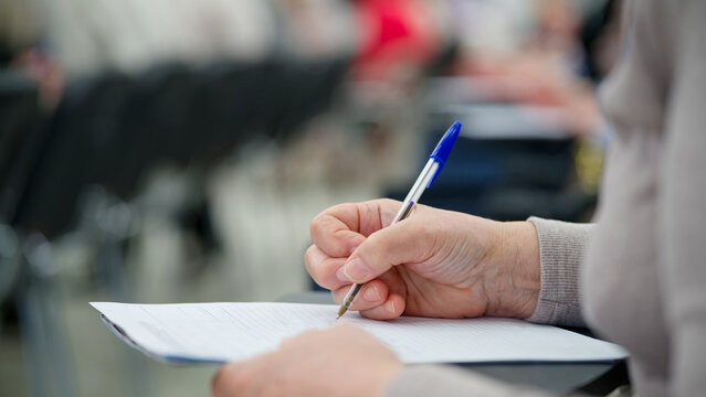 Woman hand writing on a document with pen during lecture, test or office registration. Paper form completion, education, paperwork and professional training concept. Photo