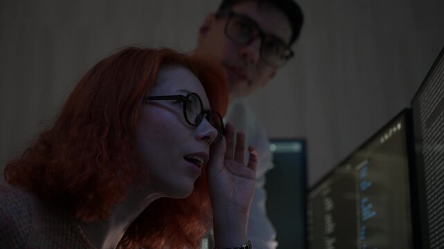 Two software developers collaborating at night, focusing on code review and debugging process on a computer screen, representing teamwork, innovation, and modern software development workflow.