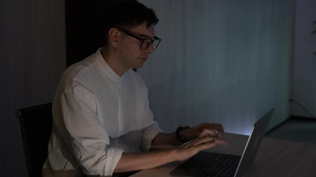 Focused young female software developer programming code on multiple monitors in a dark home office at night. Professional woman engineer working on cyber security and data science tech project.