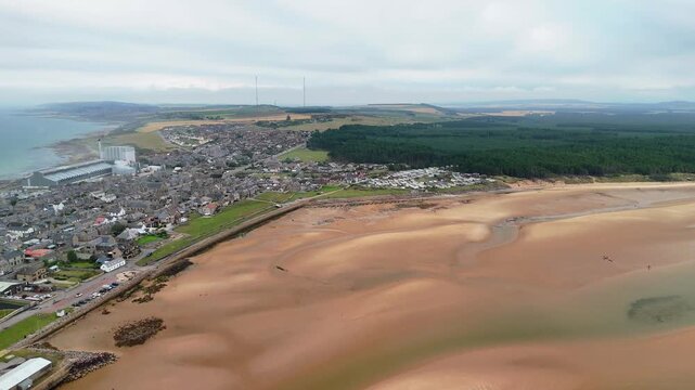 Aerial drone approach to Burghead coastal town and large sandy beach, Moray Firth, Scotland