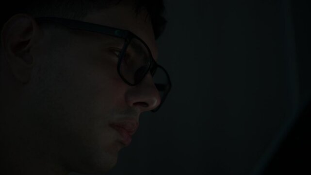 Focused young female software developer programming code on multiple monitors in a dark home office at night. Professional woman engineer working on cyber security and data science tech project.