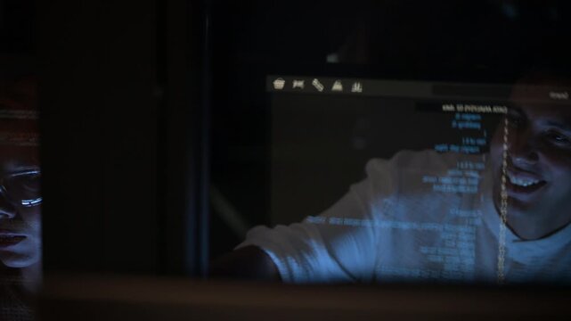 Two software developers collaborating at night, focusing on code review and debugging process on a computer screen, representing teamwork, innovation, and modern software development workflow.