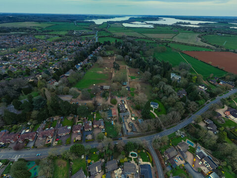 Aerial view of Rutland Farm Park with its green paddocks, farm buildings, and surrounding residential houses in Oakham, England, United Kingdom.