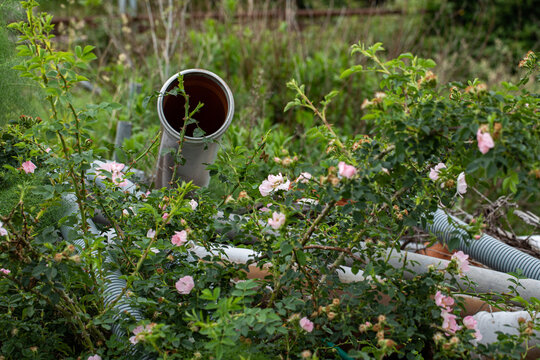 grandi tubi di plastica ed altri materiali edili abbandonati in mezzo alla vegetazione,  concetto di abbandono di rifiuti in un ambiente naturale ed inquinamento della natura