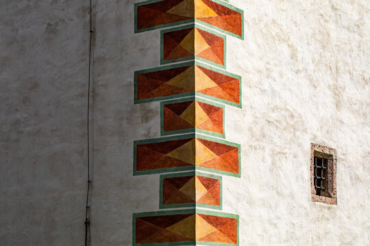 angolo che divide due pareti bianche di un edificio, per met&agrave; alla luce e per met&agrave; in ombra, decorato con disegni di  forma geometrica rettangolari di color arancione