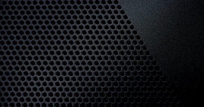 Black Perforated Metal Mesh. Smooth slow movement across extreme close-up of dark perforated metal grid with dramatic side lighting.