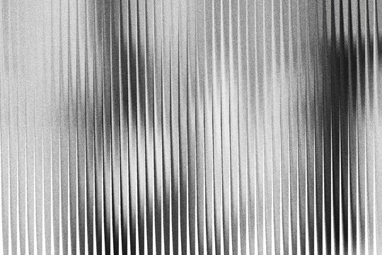 A grayscale image with vertical lines of varying shades and widths on a textured surface background