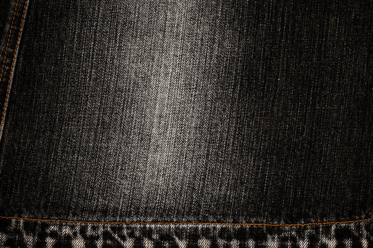 Denim fabric with dark color and visible texture showing folds and seams in an indoor setting