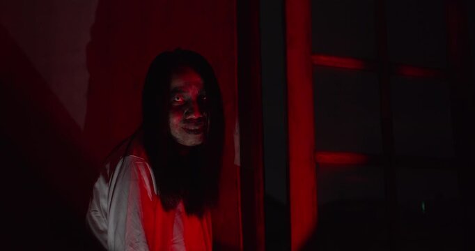 A terrifying ghost woman with a demonic grin reaches out from the darkness in a haunted house, creating a cinematic horror scene for a Halloween production.