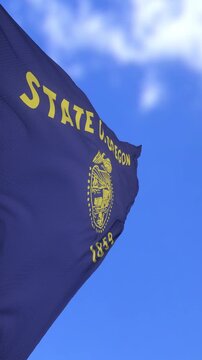 Oregon State Flag Waving in Bright Blue Sky From Low Angle