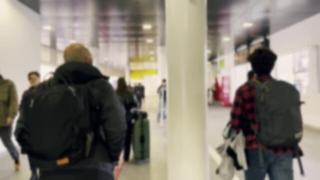 Anonymous crowd of travelers with luggage walking through a bright, blurry corridor in a modern airport or train station, showcasing the bustling atmosphere of public transportation and travel