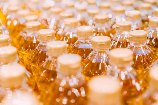 Rows of golden cooking oil plastic bottles arranged in production line with bokeh background, food manufacturing and consumer goods concept, vegetable oil product packaging retail commercial