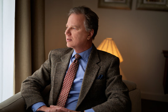 Confident middle-aged man sitting in an armchair at home