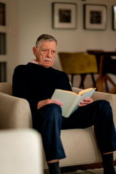 Elderly man at home reading a book