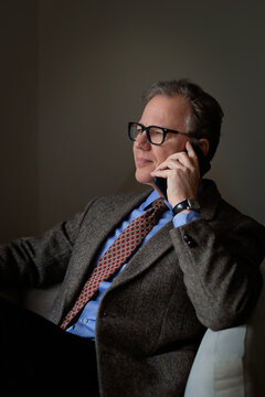 Confident middle-aged man with smart phone sitting in an armchair