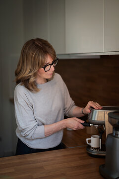 Woman standing in her kitchen and making coffee
