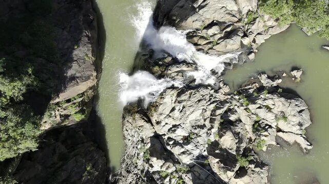 Drone flies east in bird's eye view above Lulushwana River and Mantenga waterfall on a sunny day in Ezulwini, Eswatini