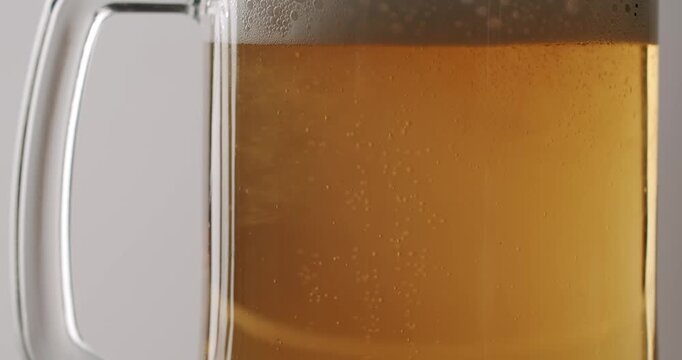 Bubbles rising in a glass of fresh, light beer creating a refreshing foam head on top, Carbonated golden beer with bubbles rising in a frosty cold glass mug covered with condensation droplets