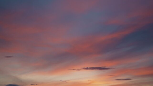 The calm movement of fluffy colorful clouds across the blue sky at sunset. Heavenly timelapse, calm, windless weather.
