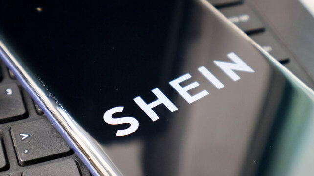 A close-up view of a laptop screen displaying the SHEIN logo on a keyboard
