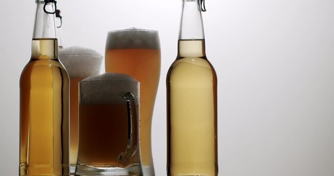 Dramatic lighting change on a collection of beer glasses and bottles with foam, Refreshing amber, light, and dark ale or lager with foam ready for tasting.