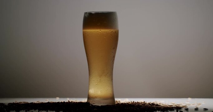 Close-up of a refreshing glass of cold light beer with rising bubbles and thick foam head, featuring condensation droplets on the exterior surface against a dark black background