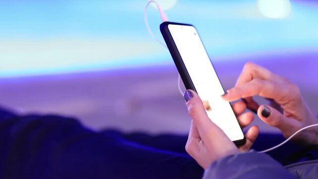 Woman using smartphone by pool at night &ndash; glowing screen, copy space, modern lifestyle.