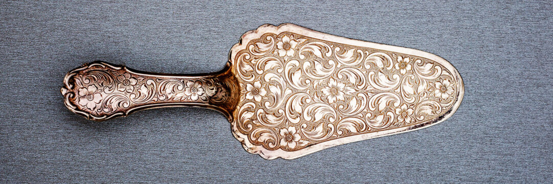 Vintage cake server with floral design on a gray background, showcased in a flat lay position for display and appreciation