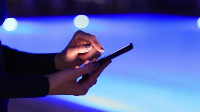 Woman using smartphone by pool at night &ndash; glowing screen, copy space, modern lifestyle.