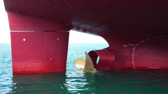 The propeller of a huge tanker sticks out halfway from the sea water and sea waves in good weather.