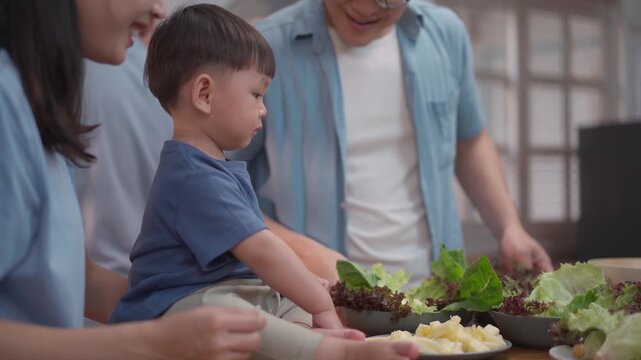 Happy multigenerational family preparing healthy meal together in kitchen, parents and grandfather bonding with child, fresh food and warm lifestyle concept