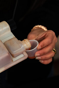 hand pouring a shot of Whiskey into a plastic shot cup