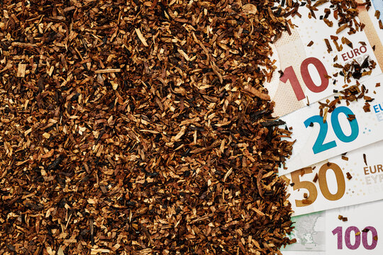 Various euro banknotes next to chopped tobacco on a flat surface in a well-lit setting
